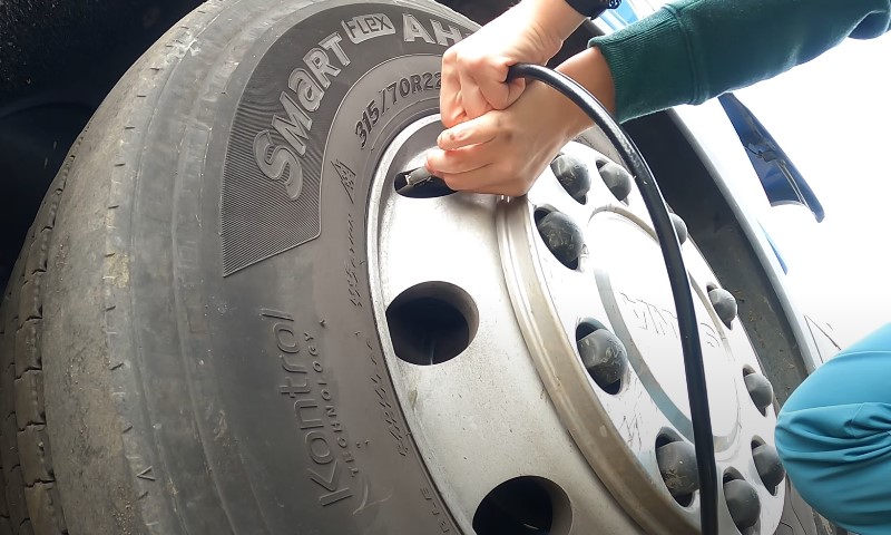 Eine Person überprüft den Reifendruck des Lkw.