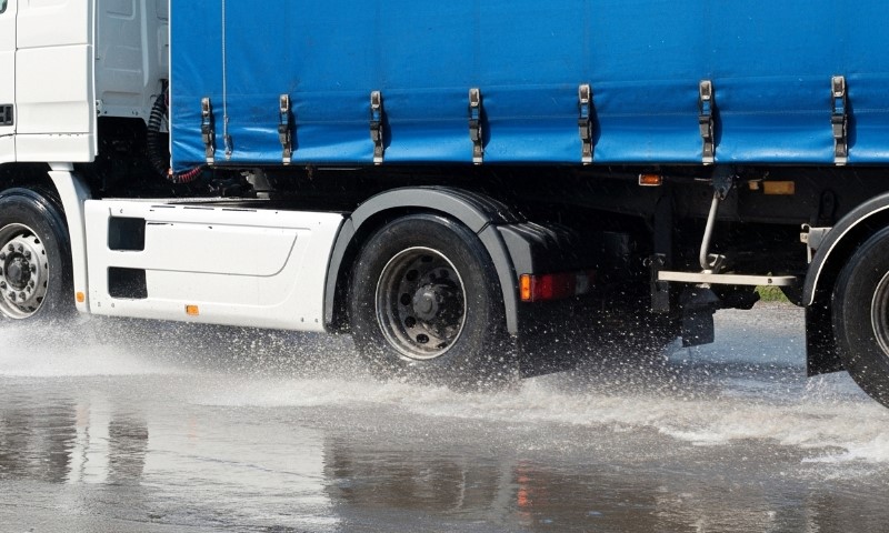 Ein großer Lastwagen fährt durch Wasser auf einer Straße