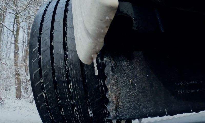 Nahaufnahme eines Lkw-Reifens im Schnee, der die winterlichen Bedingungen und die Traktion des Fahrzeugs zeigt